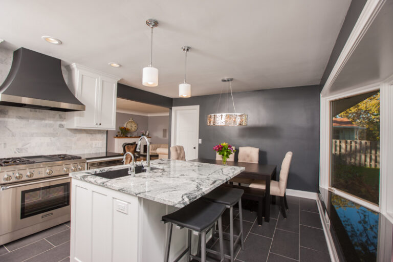 A residential kitchen with dark gray interior painting, white cabinets, marble island, and stainless appliances in Saint P...