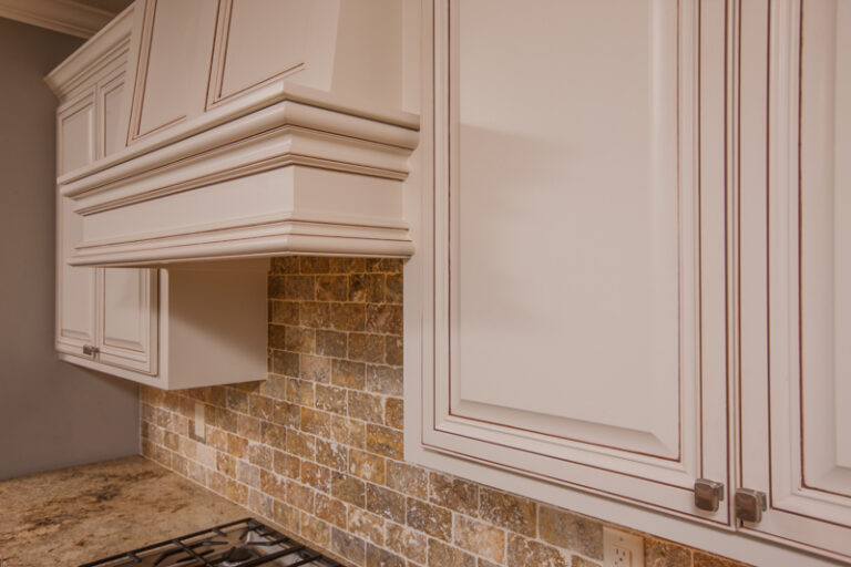Cream cabinet painting with glazed finish and stone tile backsplash in a traditional residential kitchen