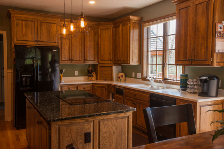 Traditional kitchen featuring oak wood cabinets and sage green walls before a painting project.