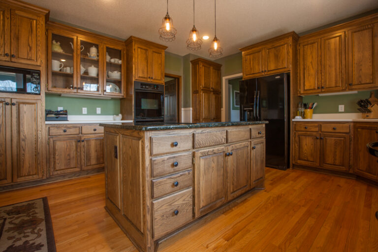 Oak wood cabinets and island in a traditional kitchen setting, prepared for a painting project.