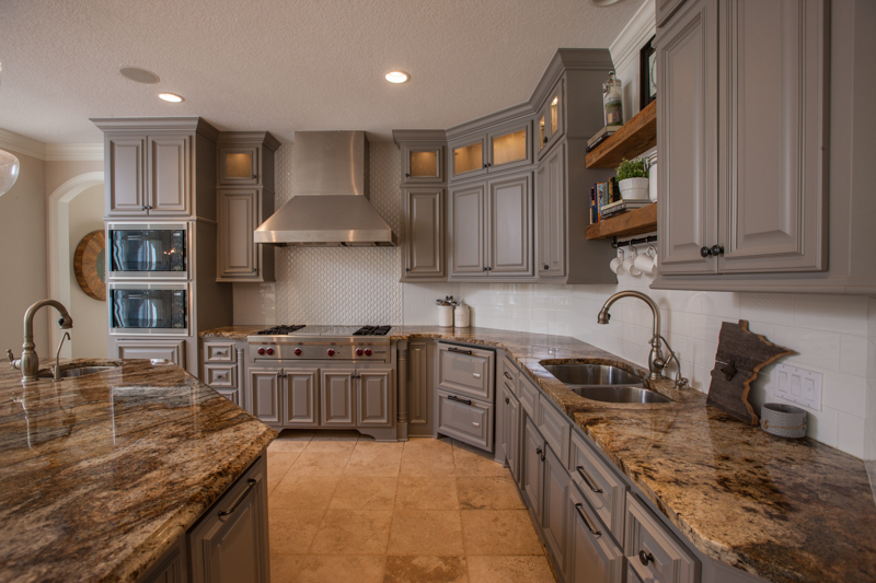 Gray painted wood kitchen cabinets with granite countertops and stainless steel appliances.