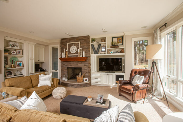 Freshly painted white built-in shelving and cabinetry in a living room with a stone fireplace.