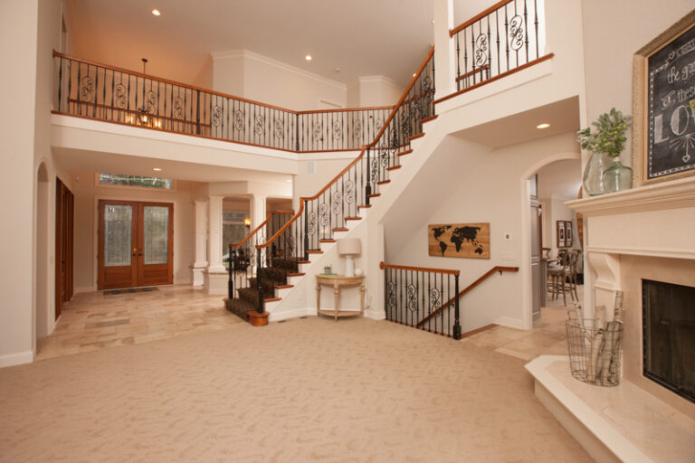 Freshly painted beige walls and white trim in a spacious living room with a grand staircase and fireplace. Painted walls and ceiling in St. Paul MN.