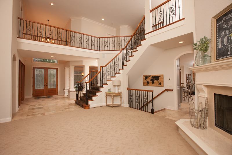Freshly painted beige walls and white trim in a spacious living room with a grand staircase and fireplace. Painted walls and ceiling in St. Paul MN.