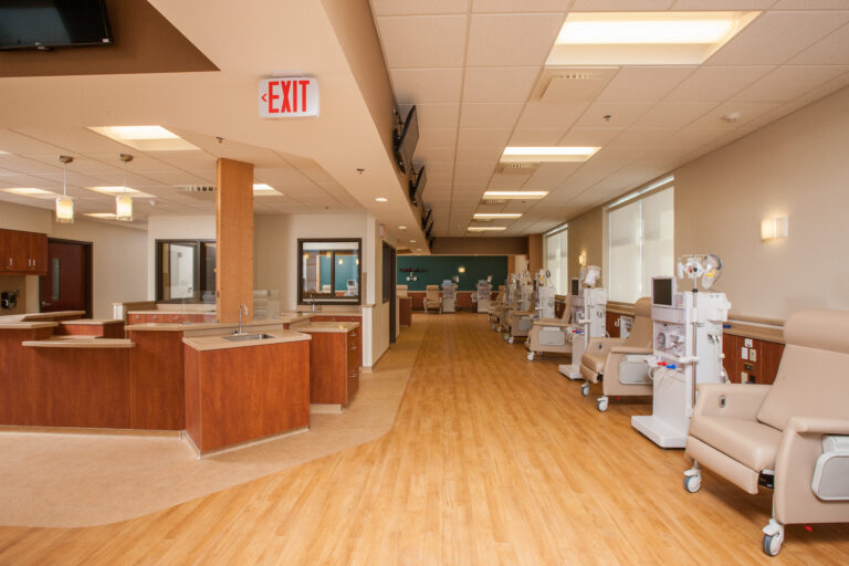 Interior painting of a modern dialysis clinic in Saint Paul with warm wood tones, beige walls, and polished hardwood floors.