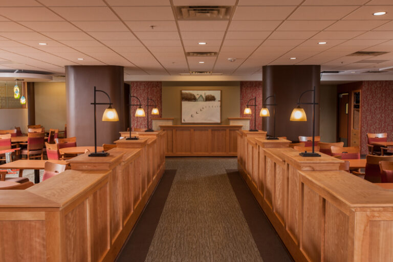 Interior painting in a Saint Paul restaurant featuring warm wood booth dividers, arc lamps, and rich burgundy and tan walls.