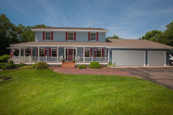 Blue two-story home with red shutters, white porch railing, and wood siding in a residential setting.