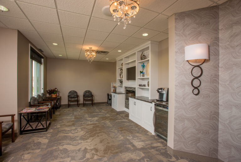 Interior painting in a modern commercial waiting room with neutral taupe walls, patterned wallpaper accent, and elegant ch...