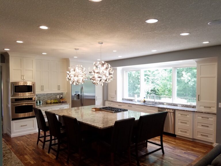 Newly painted white cabinets in a modern kitchen with a large granite island and stainless steel appliances. Painted interior walls in St. Paul Mn.