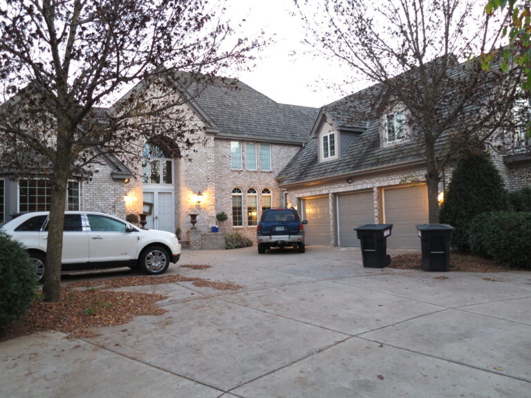 Large two-story brick residential home with exterior painting in light neutral tones, two-car garage, dusk lighting, Saint...