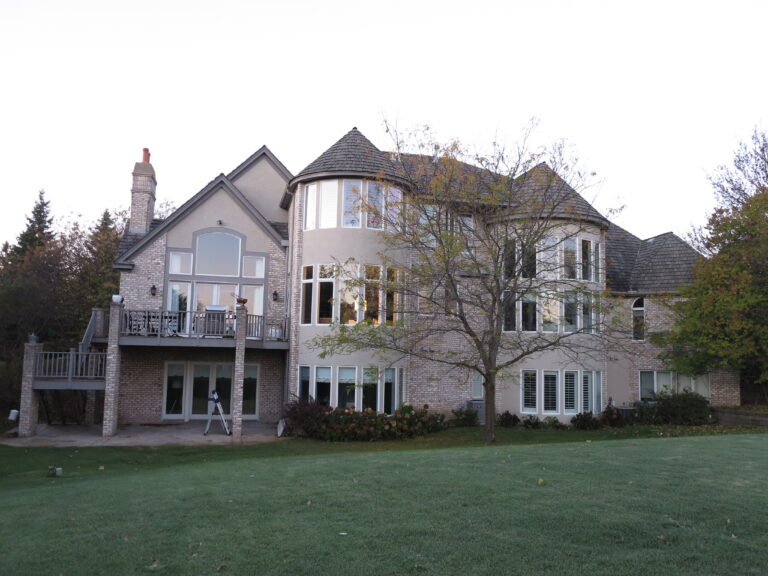 Large luxury residential home with exterior painting on stucco and brick facade, featuring turret, deck, and large windows...