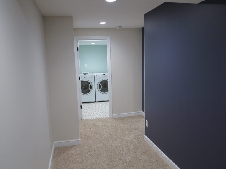 A freshly painted dark blue accent wall in a carpeted home hallway leading to a laundry room. Mississippi Blvd. St. Paul.