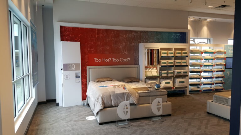 Interior painting of a retail mattress showroom with bold red accent wall, neutral tones, and modern commercial finishes i...