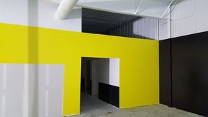 Interior painting of a commercial building featuring bold yellow and black walls with a doorway cutout design.