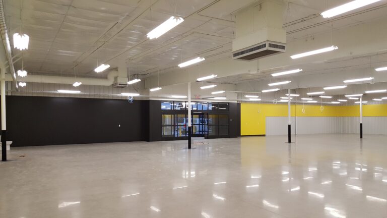 Commercial interior painting with black lower walls, yellow accent wall, and polished concrete floors in a large retail sp...