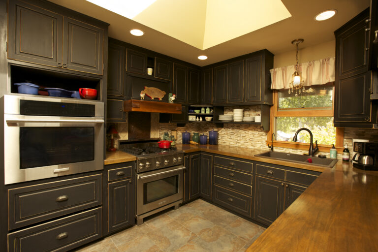 Distressed black paint finish on wooden kitchen cabinets.