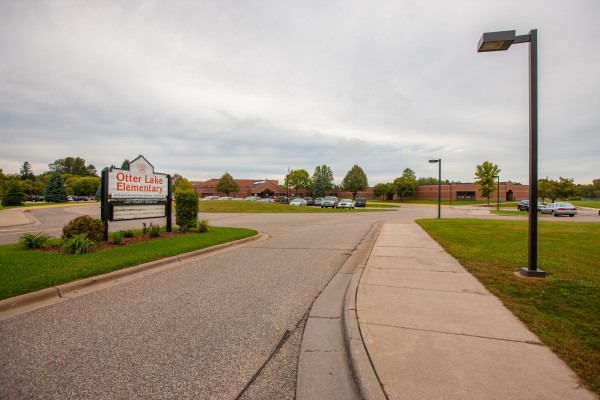 Exterior painting of Otter Lake Elementary School, a red brick commercial building with manicured grounds in Minnesota.