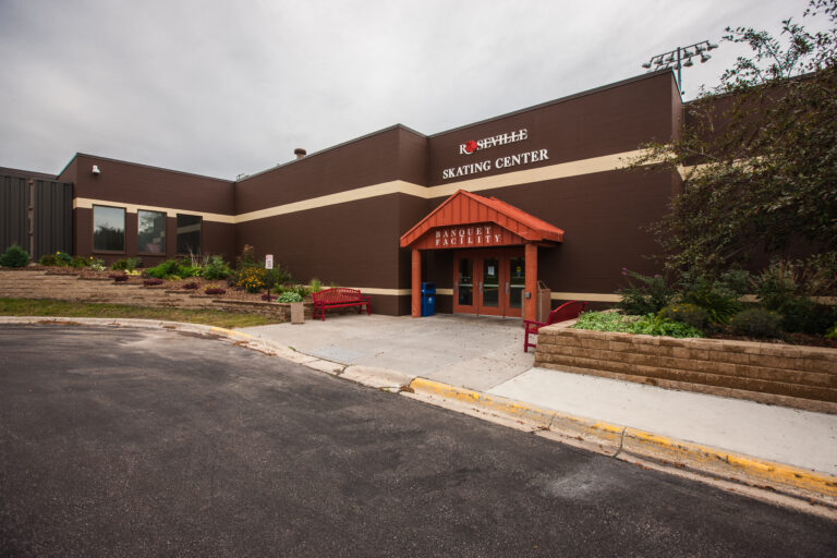 Exterior painting of brown concrete block siding with cream stripes at the Roseville Oval Skating Center banquet facility.