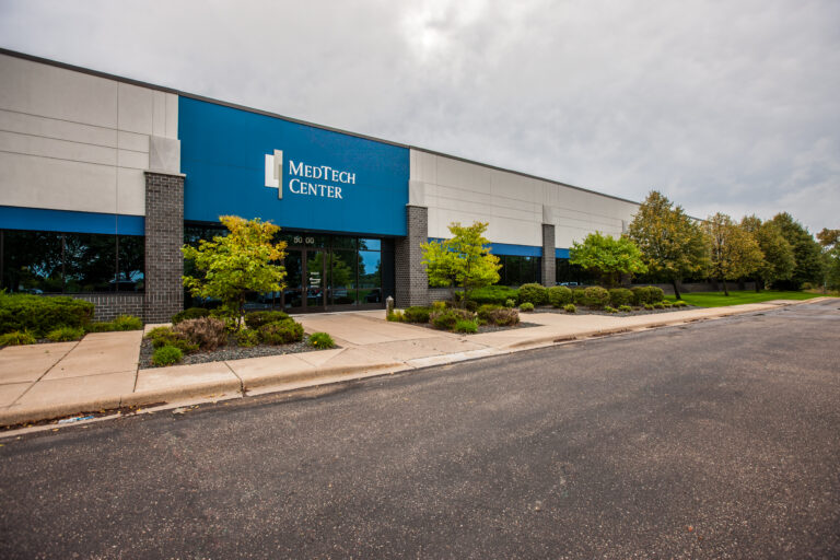 Exterior commercial painting of a blue metal facade with MedTech Center signage in an industrial park of White Bear Lakes Minnesota.