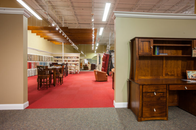 Freshly painted beige walls and white trim in a spacious furniture showroom with red carpet.