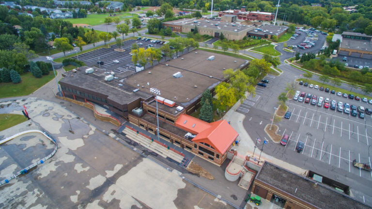 Aerial view of a commercial building exterior painting project with a bold red roof in Saint Paul, MN.