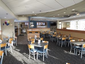 Interior painting of a commercial restaurant dining room with blue-gray walls, wood chairs, and recessed lighting in Saint...
