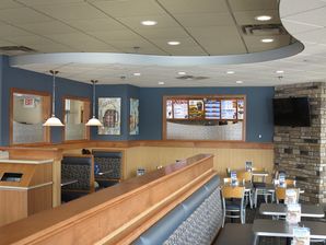 Restaurant dining area featuring dark blue painted upper walls above light wood wainscoting. Located in White Bear lakes Minnesota.