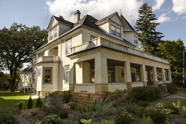 Exterior painting on a large two-story stucco home with cream walls, wraparound porch, and dormer windows in Saint Paul, MN
