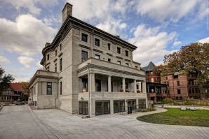 Painting the light stone exterior of a multi-story historic mansion in a neighborhood setting.