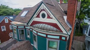 Teal wood siding and burgundy trim on a Victorian house's decorative gables and architectural trim.