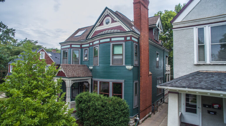 Victorian home exterior painting in teal and burgundy with decorative trim, porch, and brick chimney in Saint Paul, MN.