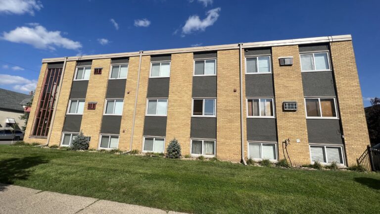 Exterior painting on a mid-century brick apartment building with tan brick and dark gray panels in Saint Paul, MN