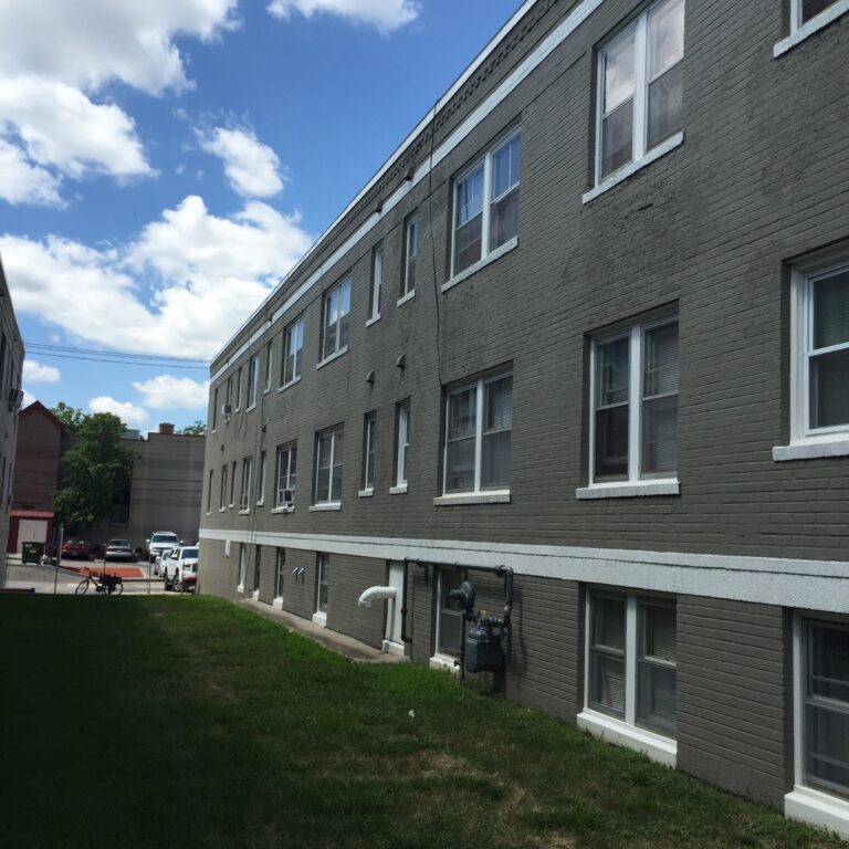 Three-story brick apartment building with gray exterior painting, white trim, green lawn, Saint Paul, MN