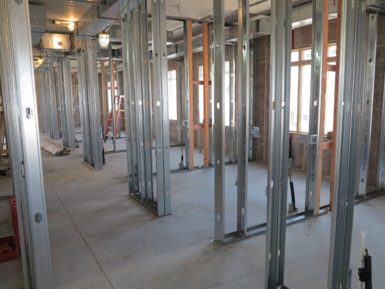 Interior framing of a building showing metal and wood wall studs on a concrete floor during construction.
