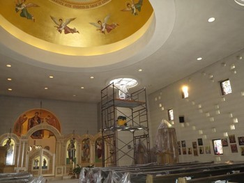 Scaffolding for a ceiling painting project inside a church with a golden dome and religious murals.